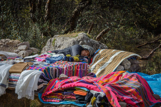 Женщина, спящая на традиционных одеялах на улице, Куско, Перу — стоковое фото