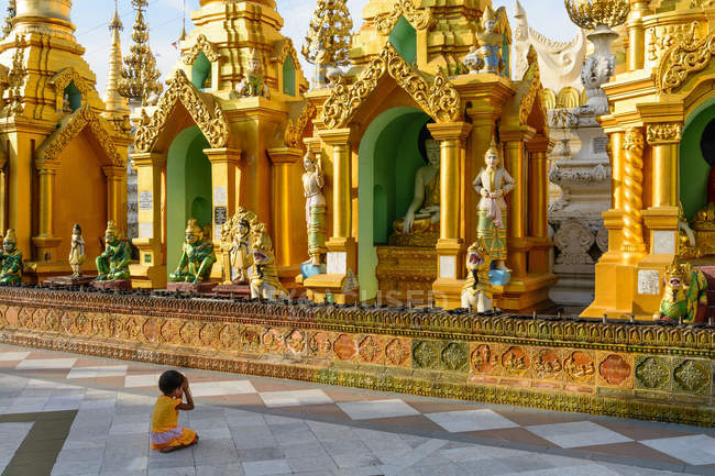 Myanmar, Región de Yangón, niño rezando de rodillas frente a la pagoda Shwedagon - foto de stock