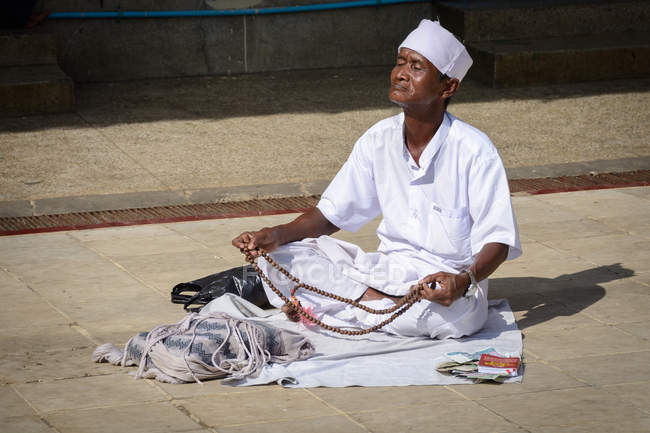 Man in white clothes pray sitting on floor at Botataung Pagoda, Rangún, Rangún, Myanmar - foto de stock