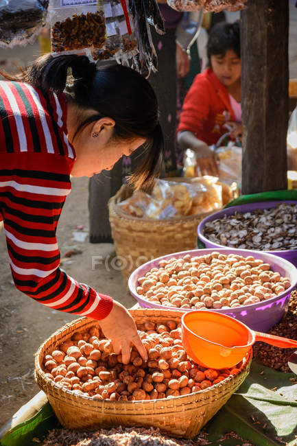 Mujer elegir productos en Phaung Daw U Pagoda mercado callejero, Nyaungshwe, Shan, Myanmar - foto de stock