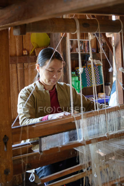 Mujer madura trabajando en telar giratorio, tejido de seda de loto, Taunggyi, Shan, Myanmar - foto de stock