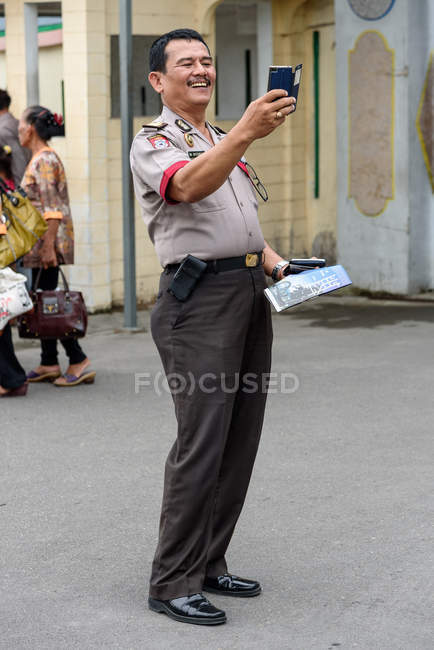 Індонезія, Суматера Утара, Кабул Лангкат, поліцейський фотографував туристів. — стокове фото
