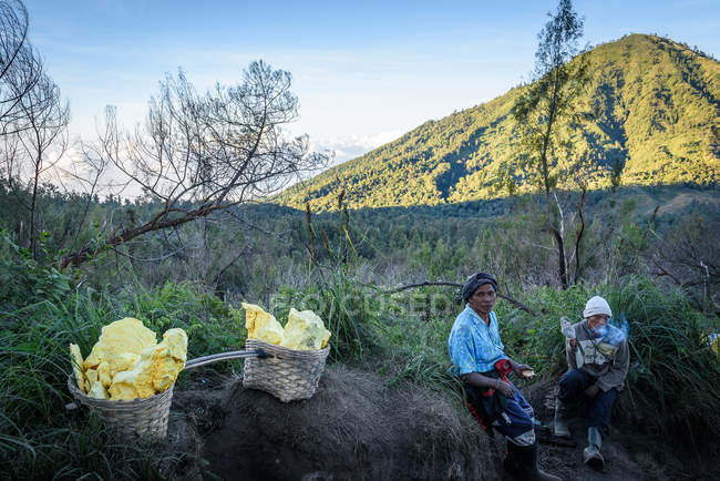 JAVA, INDONESIA - 18 GIUGNO 2018: lavoratori dello zolfo che riposano durante il trasporto dello zolfo dal vulcano Ijen — Foto stock