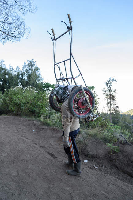 JAVA, INDONESIA - JUNE 18, 2018: sulfur worker lifting carriage climbing up on Ijen volcano — Stock Photo