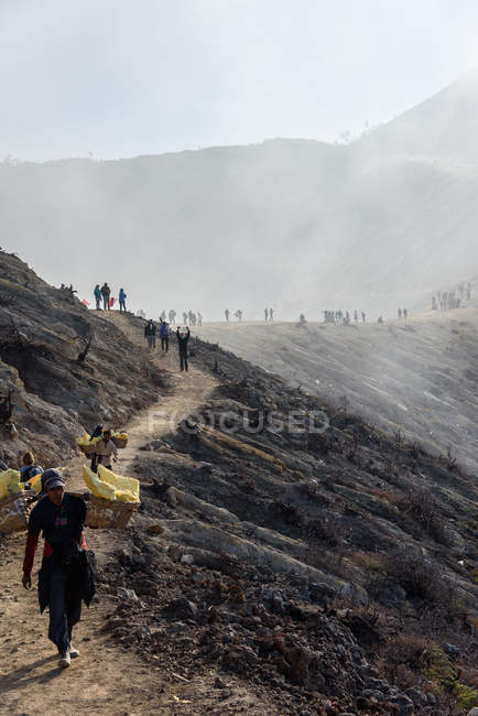 JAVA, INDONESIA - 18 DE JUNIO DE 2018: trabajadores que transportan azufre del volcán Ijen - foto de stock