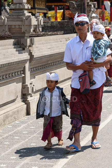 Indonesia, Bali, Kaban Tabanan, padre con dos hijos en ropa tradicional - foto de stock