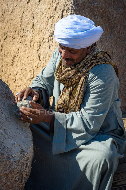 Egipto, Asuán Gouvernement, Asuán, guardián que demuestra el antiguo trabajo de piedra egipcio - foto de stock