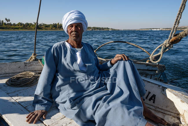 Hombre maduro en turbante azul en barco de río, Asuán, Gobierno de Asuán, Egipto - foto de stock