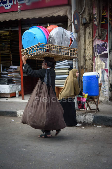 Egipto, la gobernación de El Cairo, El Cairo, hombre llevando cuencos en la cabeza en el bazar - foto de stock