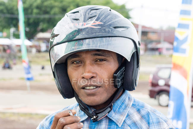 Азиатский мужчина в шлеме и сигарете в Jailolo, Kabupaten Halmahera Barat, Maluku Utara, Индонезия — стоковое фото