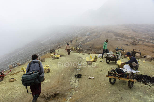 JAVA, INDONÉSIA - 18 DE JUNHO DE 2018: trabalhadores que transportam enxofre do vulcão Ijen — Fotografia de Stock