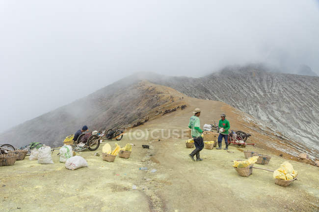 JAVA, INDONESIA - 18 DE JUNIO DE 2018: trabajadores que transportan azufre del volcán Ijen - foto de stock