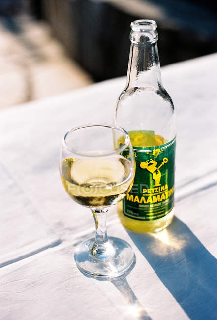 Bouteille de vin Retsina à côté du verre à vin, Neos Marmaras, Makedonia Thraki, Grèce . — Photo de stock