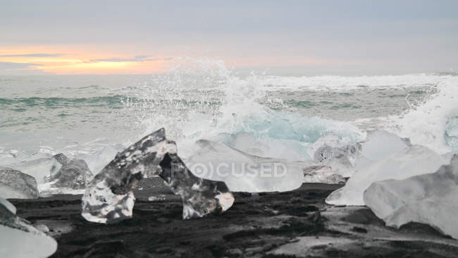 Rompehielos en la superficie de la playa de arena negra de Islandia a la luz del sol - foto de stock
