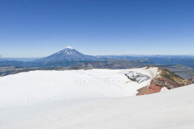 Chile, Quetrupillan Volcano top over snowy mountains landscape — Stock Photo