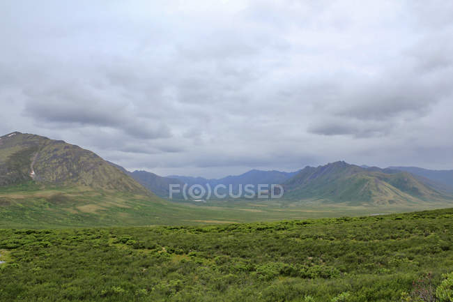 Canada, Yukon Territory, Yukon, On the Dampster Highway Julgando a paisagem selvagem do norte com montanhas sob o céu pesado — Fotografia de Stock