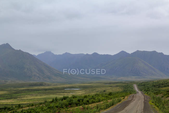 Canada, Yukon Territory, Yukon, On the Dampster Highway Julgando a paisagem selvagem do norte com montanhas sob o céu pesado — Fotografia de Stock