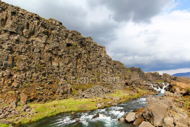 Felsiger Fluss von Berg zu Berg unter bewölktem Himmel, Island — Stockfoto