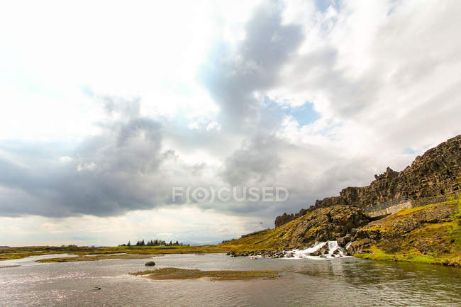Fluss und wolkenverhangener Himmel in isländischer Landschaft — Stockfoto