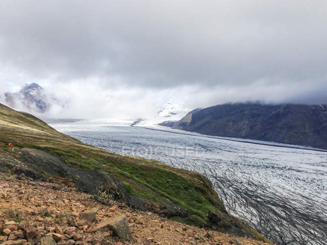 Ледник между горами и низкими облаками, Исландия — стоковое фото