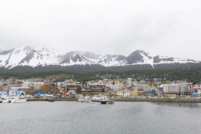 Argentina, Tierra del Fuego, Ushuaia, hacia la ciudad de Ushuhaia por el mar, montaña cubierta de nieve en el fondo - foto de stock