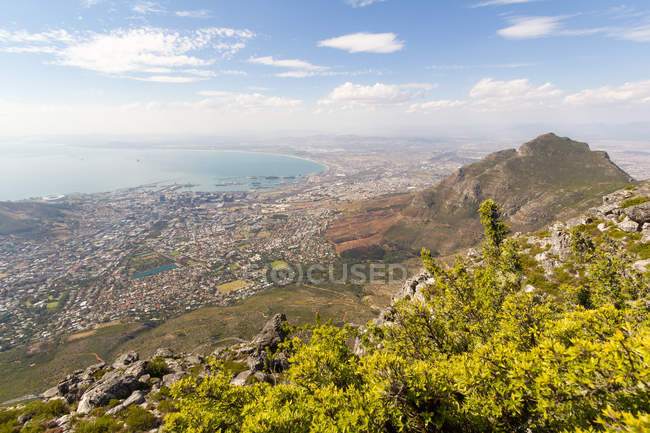 Sudáfrica, Cabo Occidental, Ciudad del Cabo vista aérea desde el Parque Nacional Table Mountain, paisaje urbano junto a la costa del océano bajo el sol - foto de stock