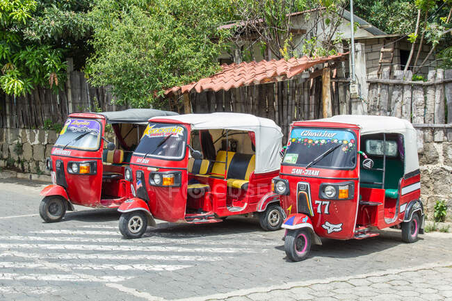 Guatemala, Solola, San Pedro La Laguna, tuk tuk vehicles on city street. - foto de stock