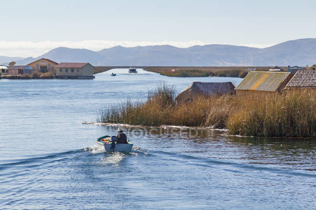 Perù, Puno, Puno, uomo in barca al lago Titikaka - Isola di Uros vista piccolo villaggio — Foto stock