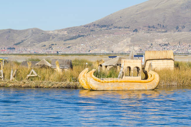 Pérou, Puno, Puno, Lac Titikaka, bateau traditionnel amarré par la jetée, montagnes en arrière-plan — Photo de stock
