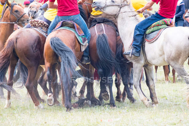 OSH REGION, KYRGYZSTAN - 22 de julio de 2017: Juegos nómadas, hombres a caballo, participantes en el polo caprino, vista trasera - foto de stock
