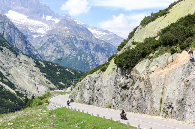 Suíça, Valais, Obergoms VS, The Furka Pass com motociclistas em estrada de montanha — Fotografia de Stock