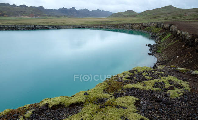 Блакитне озеро з скелястими берегами тлі гірського хребта, су Урнесі, Ісландія — стокове фото