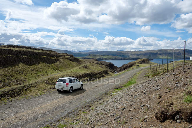 Islândia, Vesturland, Carro na estrada de cascalho para o lago — Fotografia de Stock