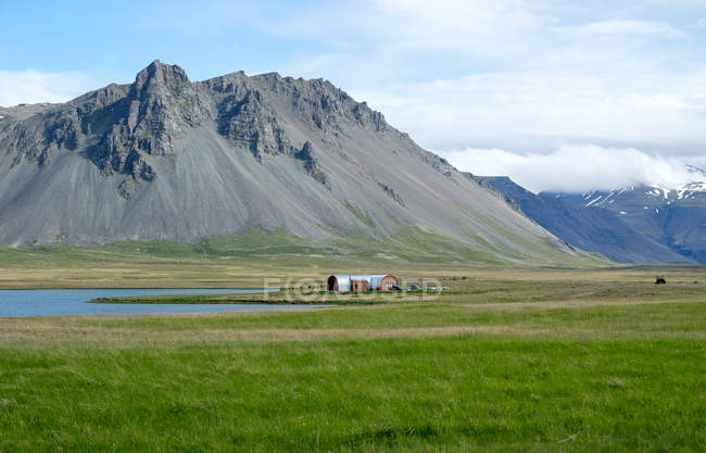Lontano edificio agricolo immerso nel verde con montagne, Snaefellsnes, Islanda — Foto stock