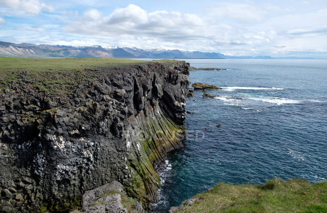 Costa escarpada y mar en la luz del sol brillante, Hellnar, Islandia - foto de stock