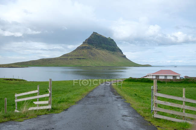 Сельский пейзаж с зеленым холмом в море, Исландия, Grundarfjorour — стоковое фото