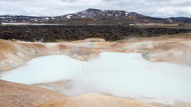 Геотермальный бассейн с паром и горами вдали, Исландия — стоковое фото