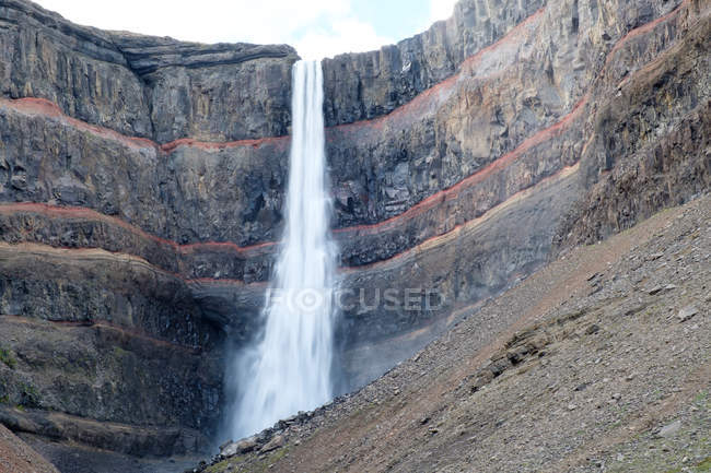 Vista panorámica de Hengifoss fluyendo en roca de rayas rojas - foto de stock