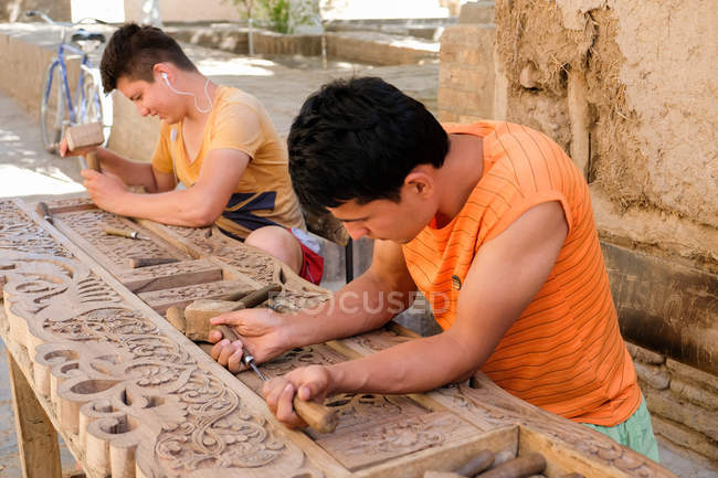 Hombres locales tallando puertas y puertas con ornamentos ornamentados en Khiva, Uzbekistán . - foto de stock