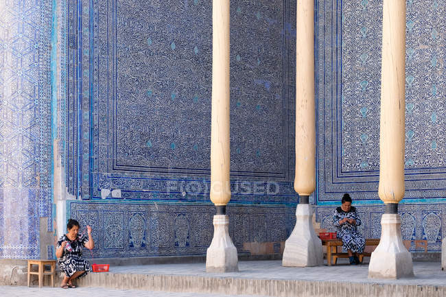 Madrasa at registan, samarkand, usbekistan - 6. Juni 2017: Frauen sitzen im Schatten einer alten madrasa und stricken — Stockfoto