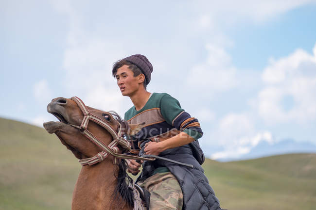 Región OSH, KYRGYZSTAN - 22 de julio de 2017: Joven montando a caballo - foto de stock