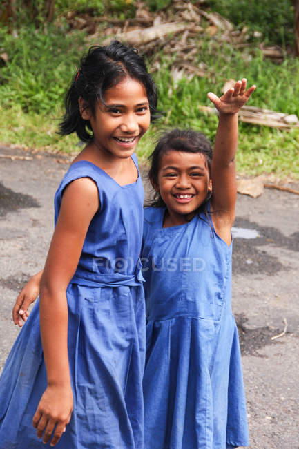 Dos chicas en vestidos azules sonriendo a la cámara, Salua, Samoa - foto de stock