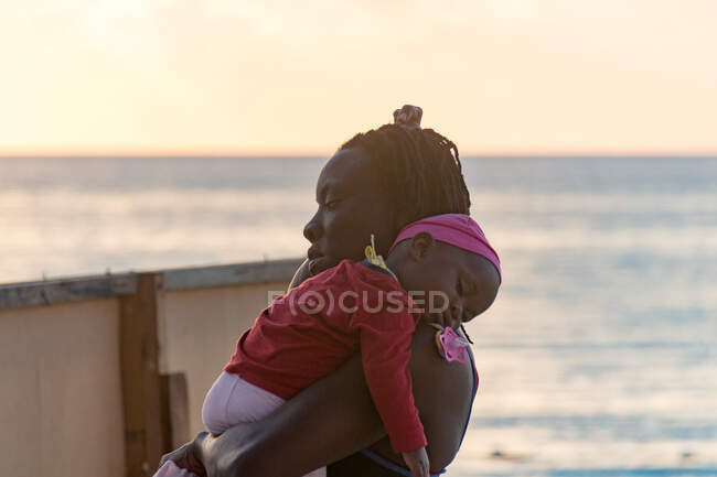 Jamaïque, Negril, heure du coucher, mère portant un bébé endormi — Photo de stock
