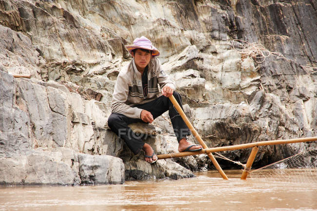 Рыбак на скалистом берегу реки Меконг, Лаос — стоковое фото