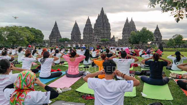 Personas haciendo yoga antes del Templo Prambanan, Daerah Istimewa Yogyakarta, Indonesia - foto de stock