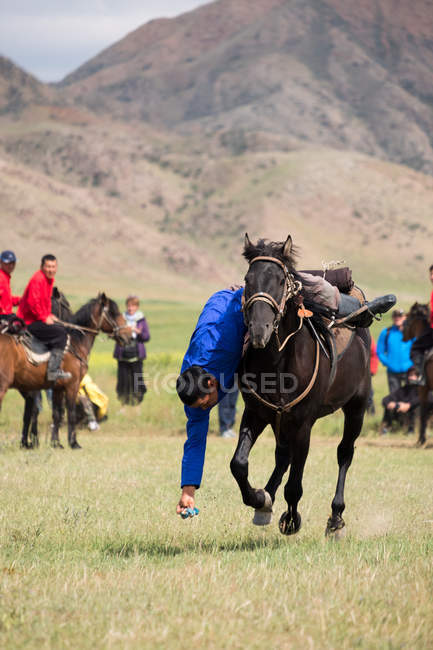 AK SAY, RÉGION D'ISSYK-KUL, KYRGYZSTAN - 12 AOÛT 2017 : exercice d'habileté au galop, jeux de nomades, hommes locaux à cheval — Photo de stock