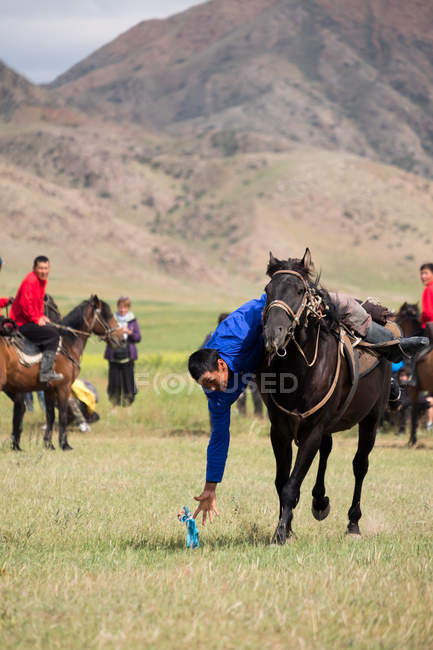 AK SAY, ISSYK-KUL REGION, KYRGYZSTAN - AUGUST 12, 2017: skill exercise in gallop, nomad games, local men riding horses — Stock Photo