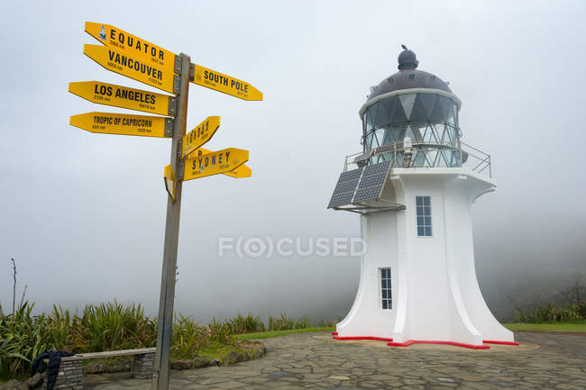 Новая Зеландия, Нортленд, мыс Рейнга, Маяк на мысе Рейнга и желтые указатели направления в туманную погоду — стоковое фото