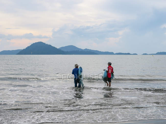 Dos pescadores sosteniendo red de pesca en el agua, Phang Nga, Tailandia - foto de stock
