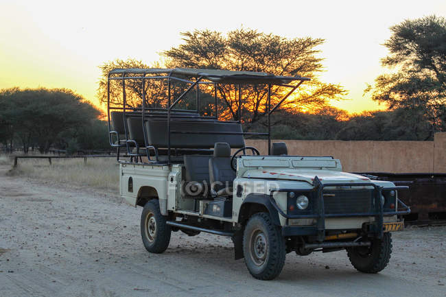 Namíbia, Okapuka Ranch, Safari, Game Drive, Safari Jeep estacionado na estrada ao pôr do sol — Fotografia de Stock